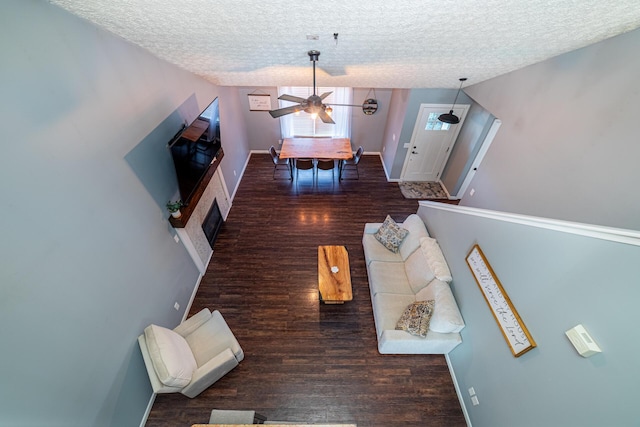 unfurnished living room featuring dark wood-style floors, ceiling fan, baseboards, and a textured ceiling