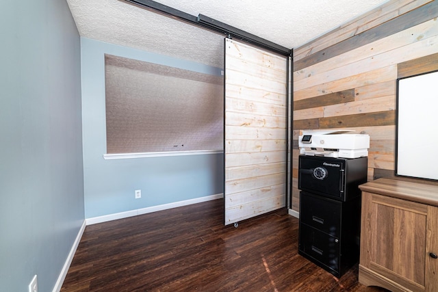 bedroom featuring wooden walls, dark wood-style flooring, a textured ceiling, and baseboards