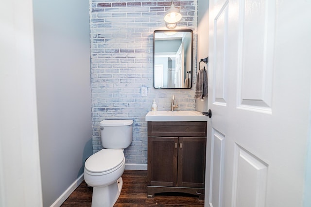 bathroom featuring toilet, baseboards, wood finished floors, and vanity