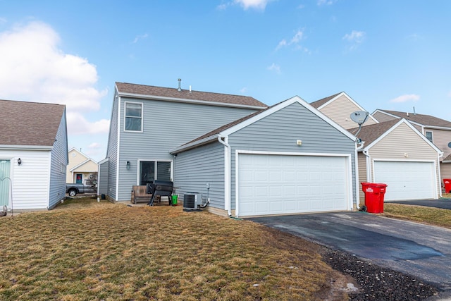 view of front of home with a garage, driveway, a front lawn, and central AC unit