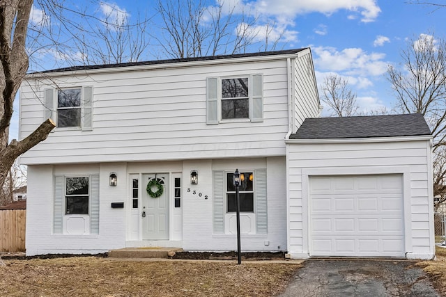 colonial-style house with a shingled roof, fence, driveway, and an attached garage