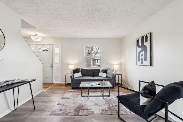 living area featuring a textured ceiling, baseboards, and wood finished floors