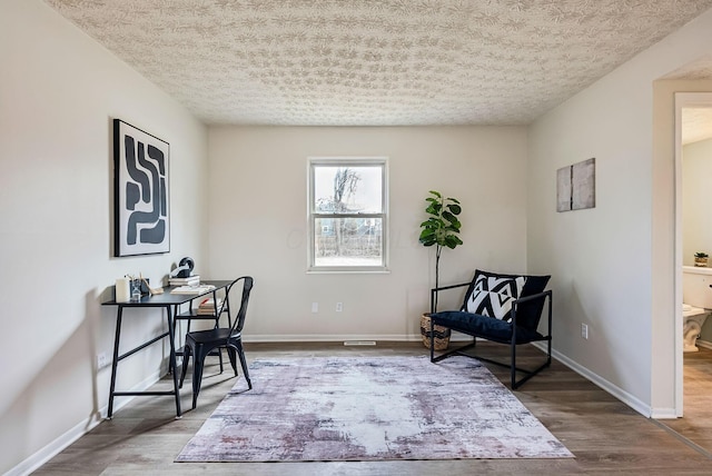 office featuring a textured ceiling, baseboards, and wood finished floors