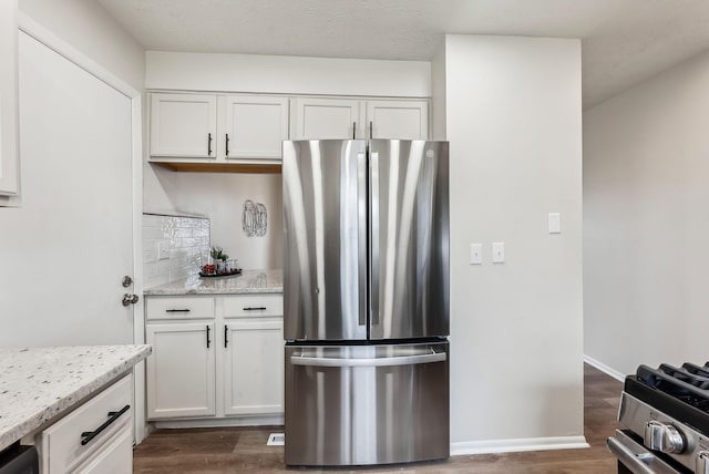 kitchen featuring appliances with stainless steel finishes, white cabinets, dark wood finished floors, and light stone counters