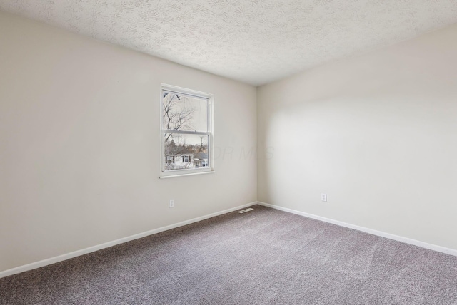 unfurnished room with carpet, baseboards, and a textured ceiling