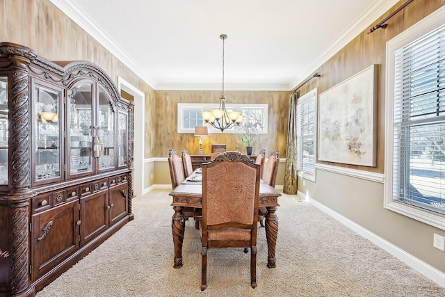 dining room featuring light colored carpet, crown molding, a notable chandelier, and baseboards