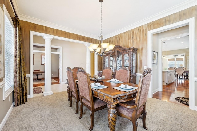 dining space with crown molding, a notable chandelier, decorative columns, and light carpet