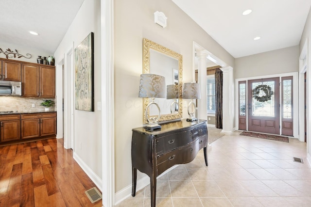 entryway with visible vents, light tile patterned floors, decorative columns, and baseboards