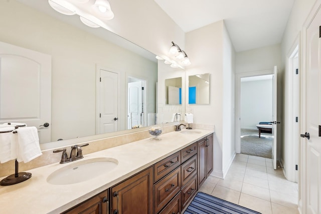 bathroom with baseboards, double vanity, a sink, and tile patterned floors