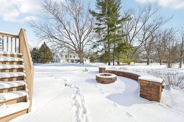 yard layered in snow with an outdoor fire pit and stairs