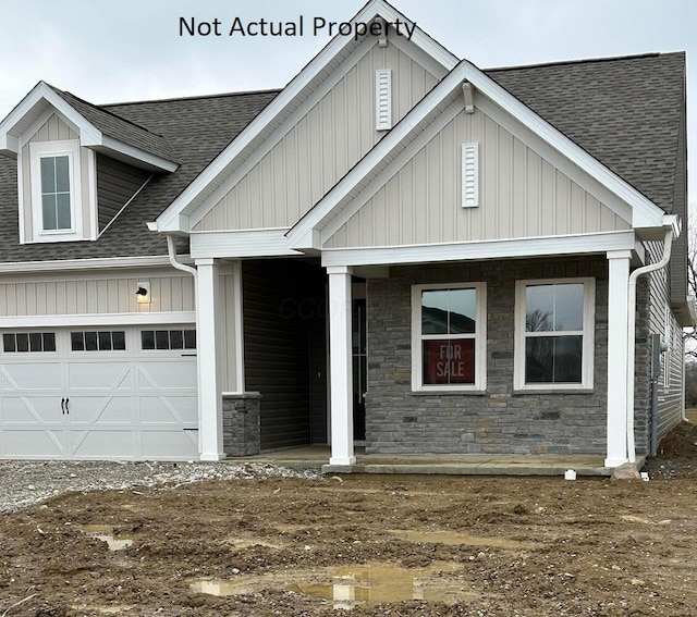 view of front of home with a garage, stone siding, and roof with shingles