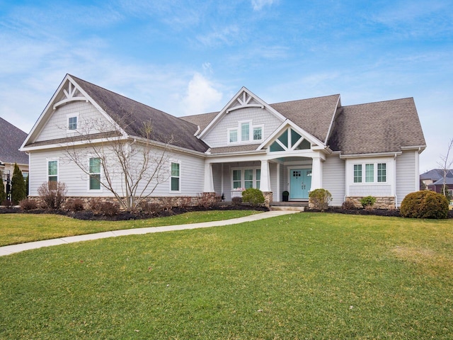 craftsman house featuring roof with shingles and a front lawn