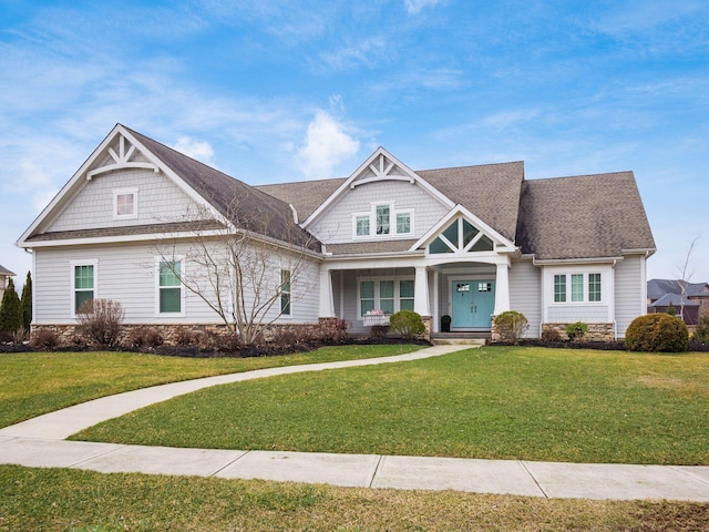 craftsman-style home with a shingled roof and a front lawn