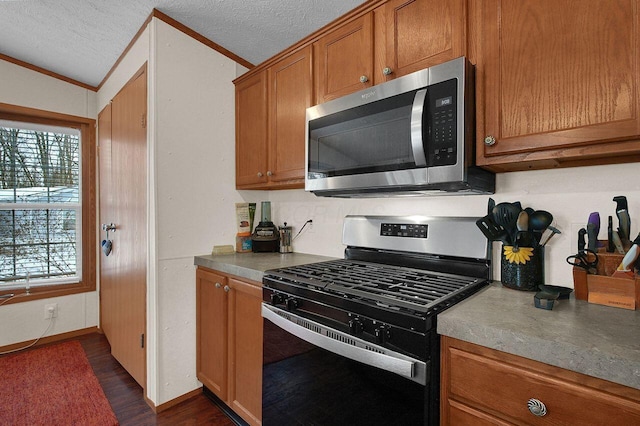 kitchen featuring dark wood finished floors, stainless steel microwave, brown cabinetry, gas stove, and a textured ceiling