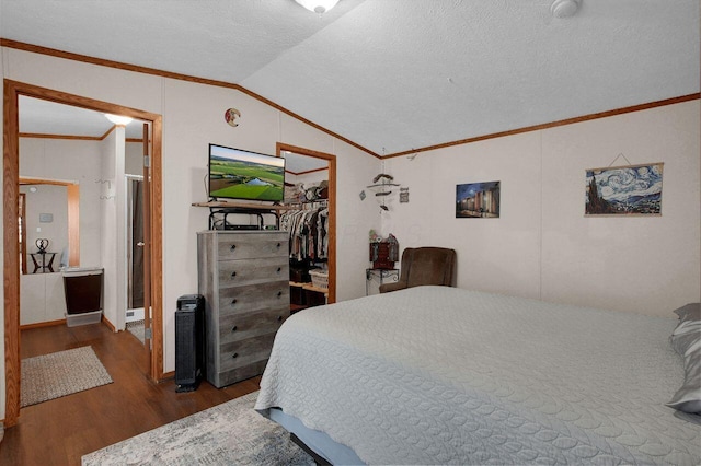 bedroom featuring lofted ceiling, dark wood-type flooring, a walk in closet, and ornamental molding