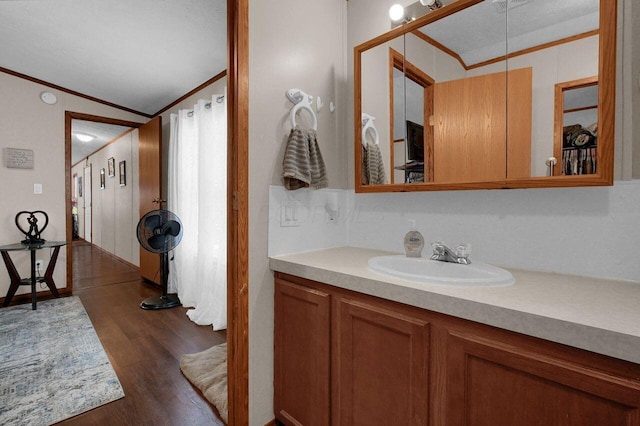 bathroom featuring crown molding, vaulted ceiling, wood finished floors, and vanity