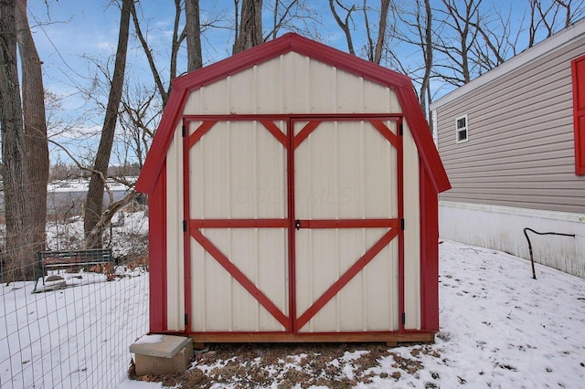 snow covered structure featuring a storage shed, fence, and an outdoor structure