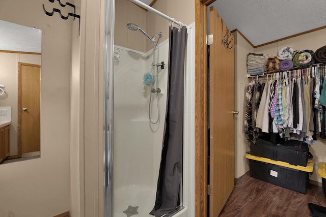 bathroom with a stall shower, crown molding, a textured ceiling, and wood finished floors