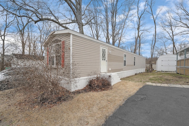 view of side of home featuring a storage shed and an outbuilding