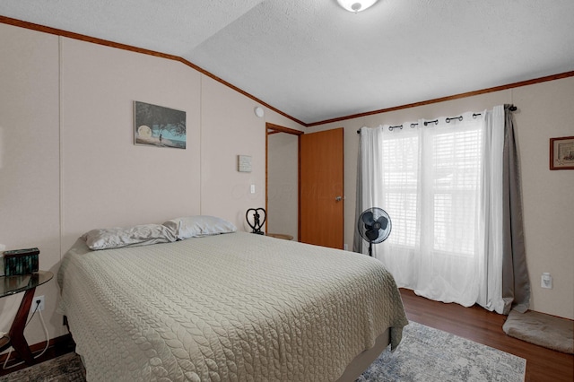 bedroom with a textured ceiling, ornamental molding, vaulted ceiling, and wood finished floors