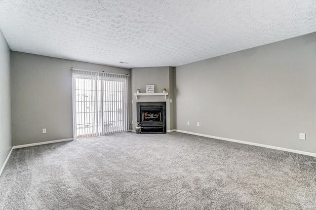 unfurnished living room featuring a textured ceiling, carpet, a fireplace with flush hearth, and baseboards