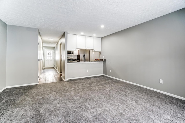 interior space featuring recessed lighting, carpet flooring, a textured ceiling, and baseboards