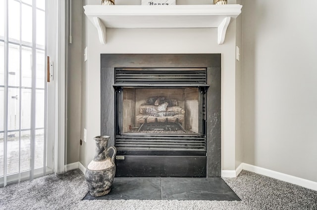 interior details with a fireplace with flush hearth, carpet flooring, and baseboards