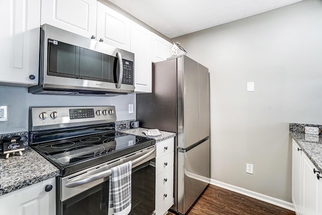 kitchen featuring stainless steel appliances, dark wood-type flooring, white cabinetry, baseboards, and dark stone counters