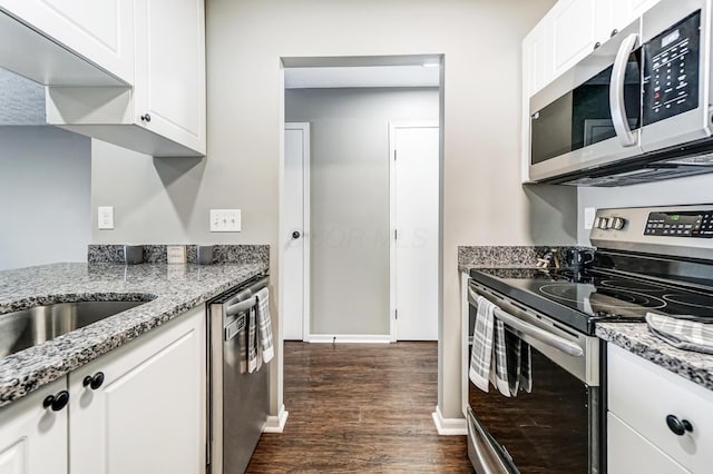 kitchen with dark wood-type flooring, baseboards, white cabinets, appliances with stainless steel finishes, and light stone countertops