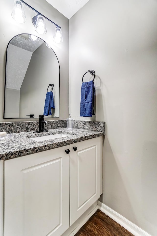 bathroom featuring baseboards, wood finished floors, and vanity