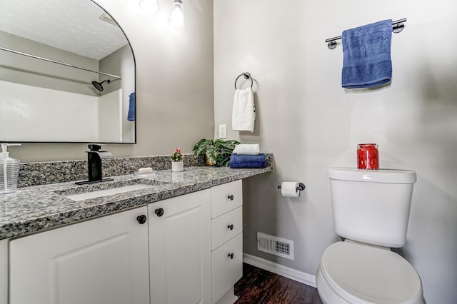 bathroom featuring baseboards, visible vents, toilet, wood finished floors, and vanity