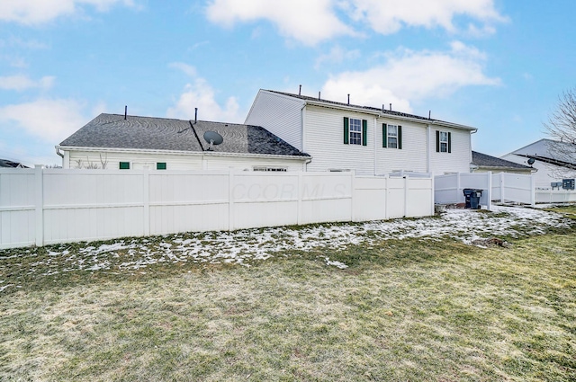 back of property with fence and a lawn