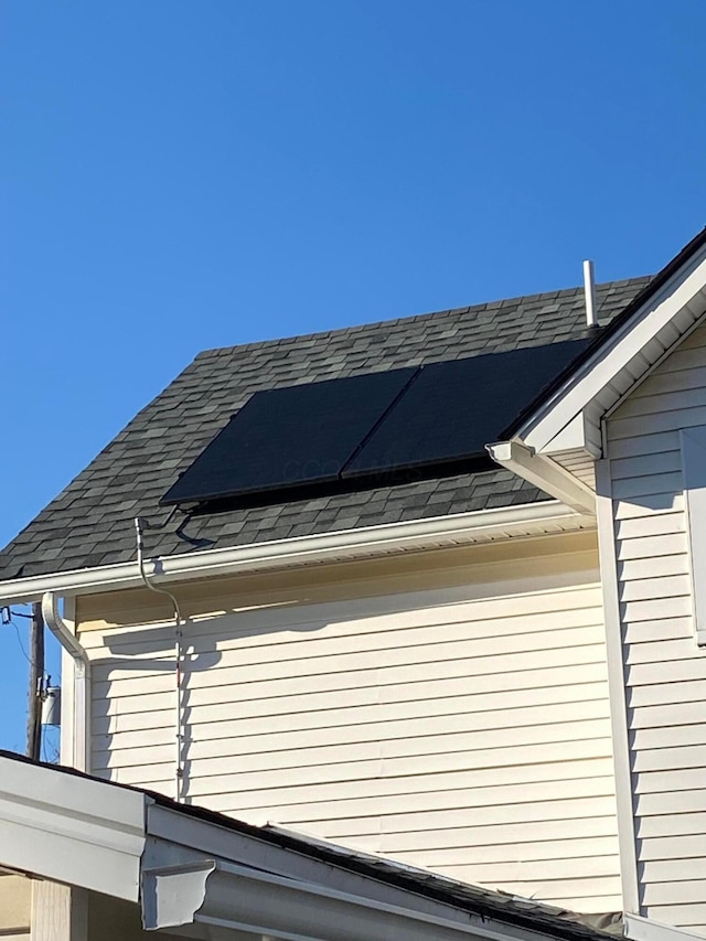 view of home's exterior featuring roof mounted solar panels and roof with shingles