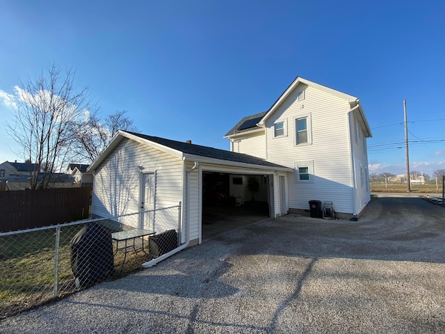 view of side of property with aphalt driveway and fence