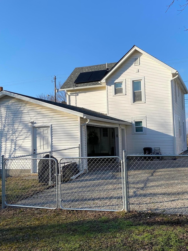 back of house featuring fence private yard, a gate, and roof mounted solar panels