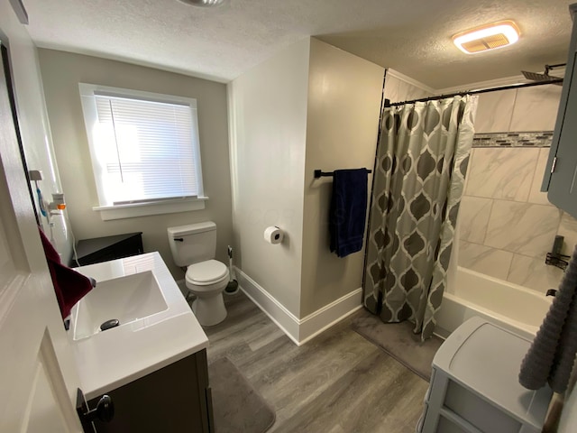 full bath featuring a textured ceiling, toilet, wood finished floors, vanity, and baseboards