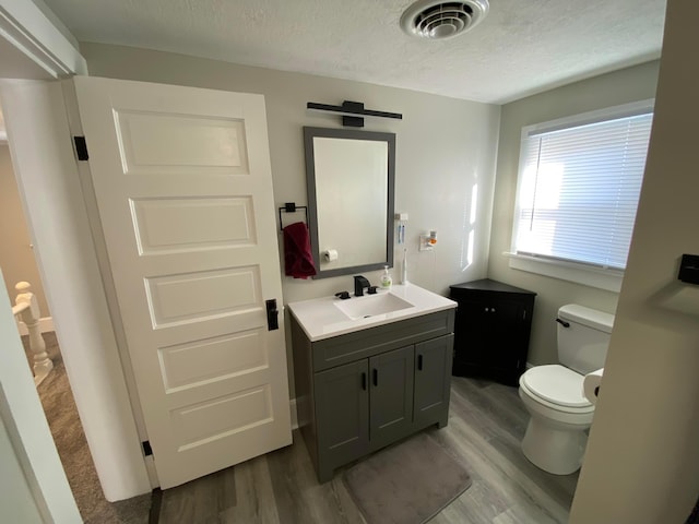 bathroom with visible vents, a textured ceiling, toilet, and wood finished floors