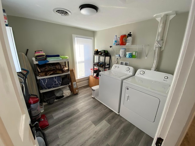 clothes washing area with laundry area, visible vents, separate washer and dryer, and wood finished floors