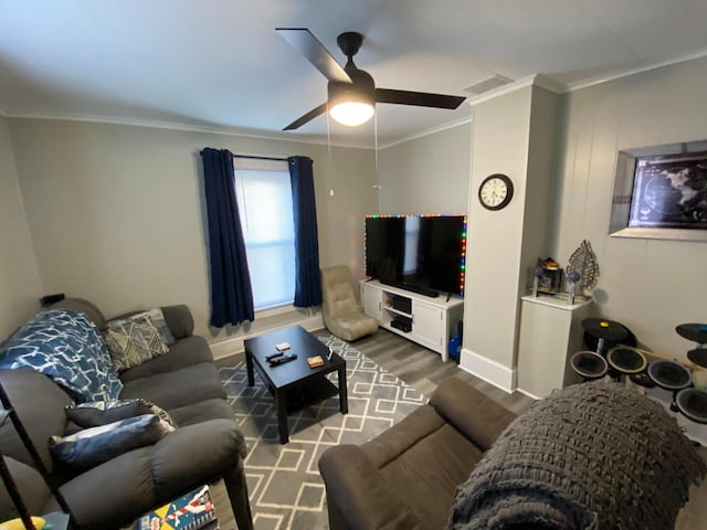 living room with visible vents, ornamental molding, a ceiling fan, wood finished floors, and baseboards