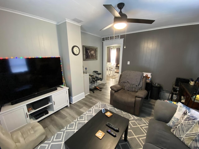 living room with crown molding, visible vents, a ceiling fan, wood finished floors, and baseboards