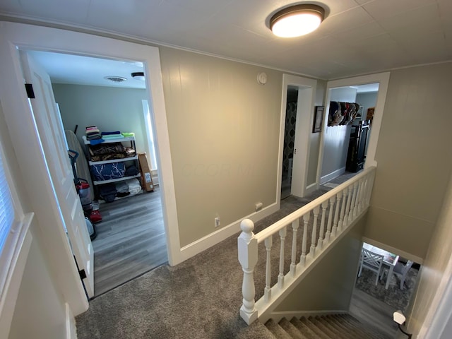 corridor with carpet floors, visible vents, and baseboards