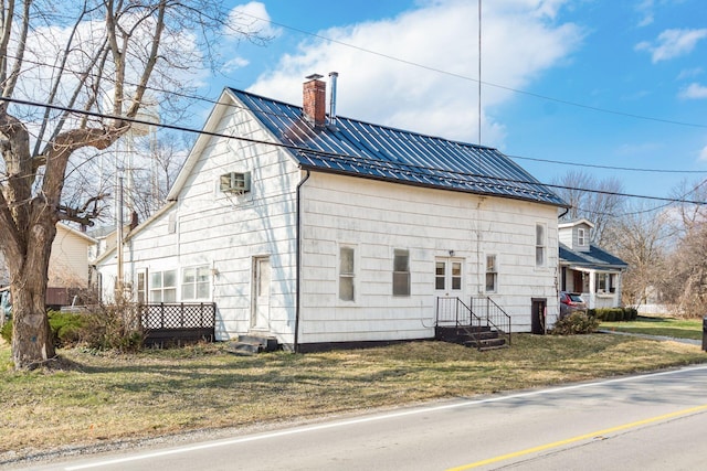 view of side of home featuring a wall unit AC, a chimney, metal roof, and a lawn