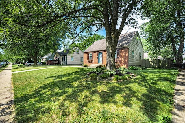 view of front facade with brick siding, crawl space, a front lawn, and fence