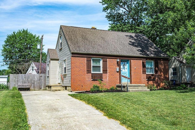 view of front of house featuring a shingled roof, fence, a front lawn, and brick siding