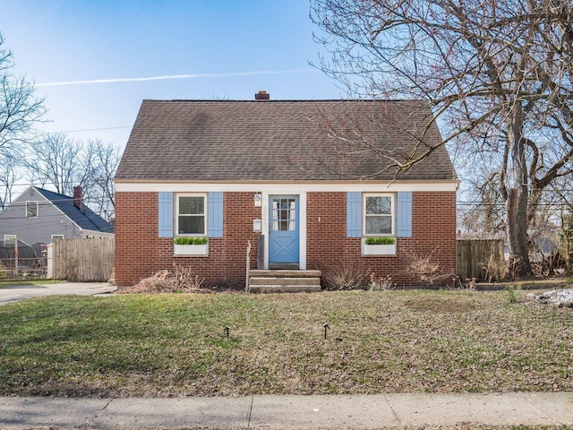 view of front of house featuring brick siding, a front yard, and fence