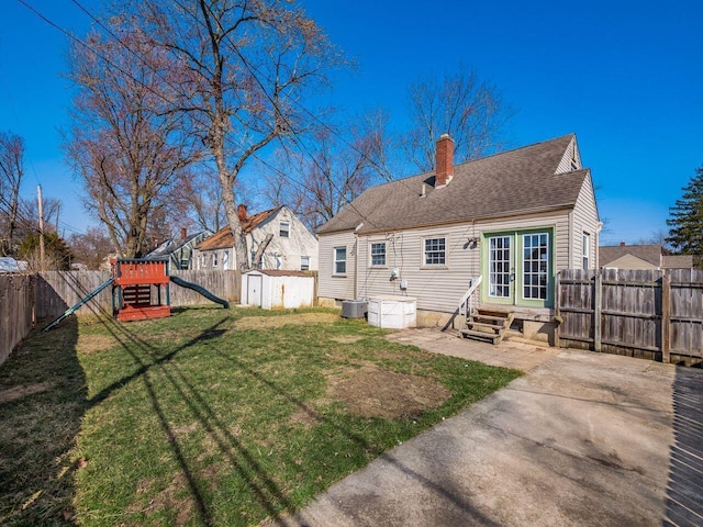 back of property featuring an outbuilding, a lawn, entry steps, a fenced backyard, and a shed