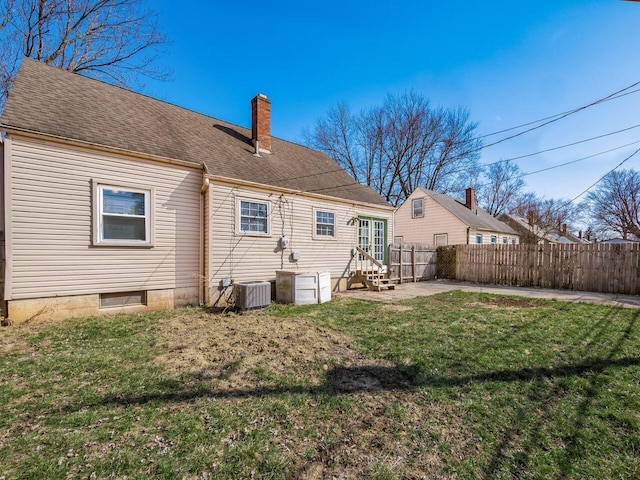 back of house with a lawn, cooling unit, a chimney, and a fenced backyard