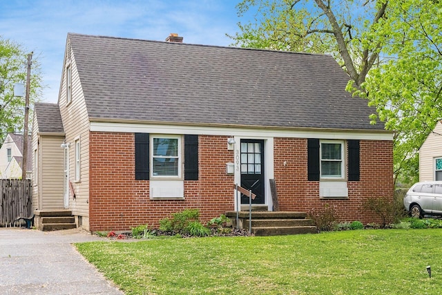 3093 Hamilton Ave, Columbus, OH 43224 - cape cod house featuring a shingled roof, a chimney, a front lawn, and brick siding