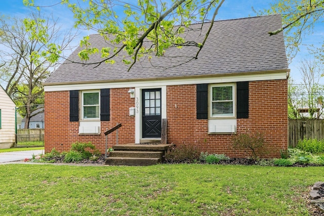 3093 Hamilton Ave, Columbus, OH 43224 - cape cod home featuring fence, a shingled roof, a front lawn, and brick siding