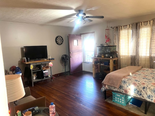 bedroom with ceiling fan, dark wood finished floors, and a textured ceiling